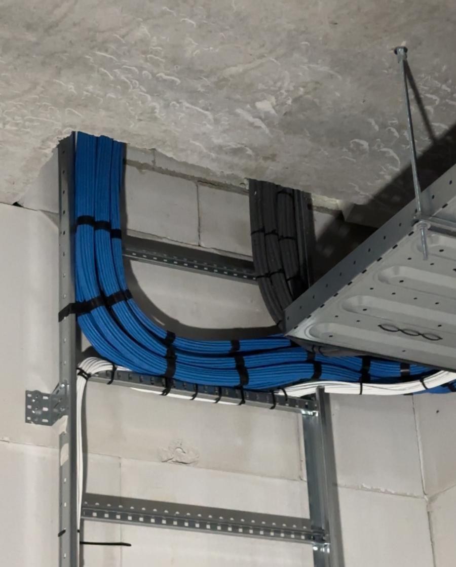 Blauwe Cat6a-bundel met ruime bocht van kabelgoot naar kabelladder