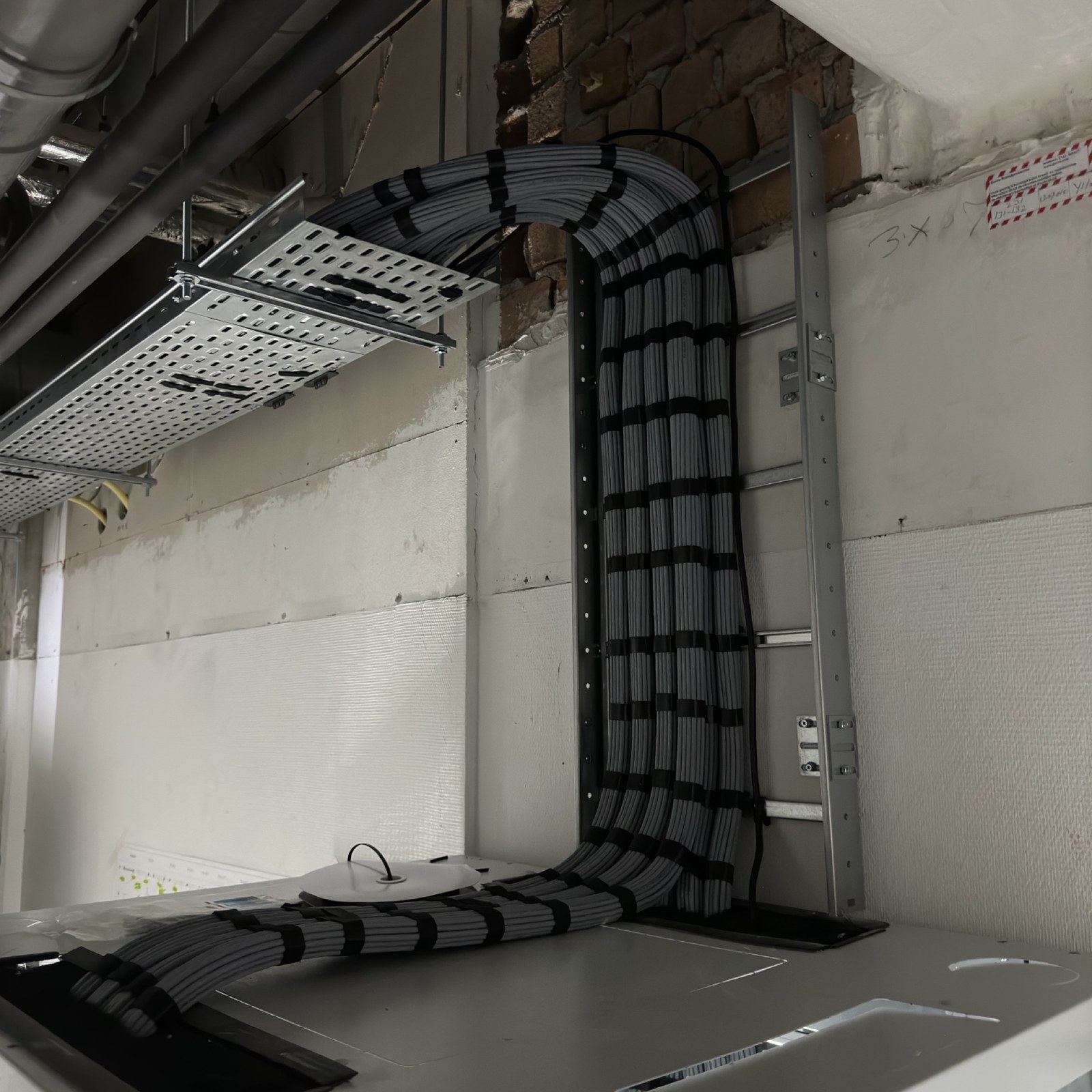 Grijze kabelbundel van kabelgoot via ladder naar de patchkast
