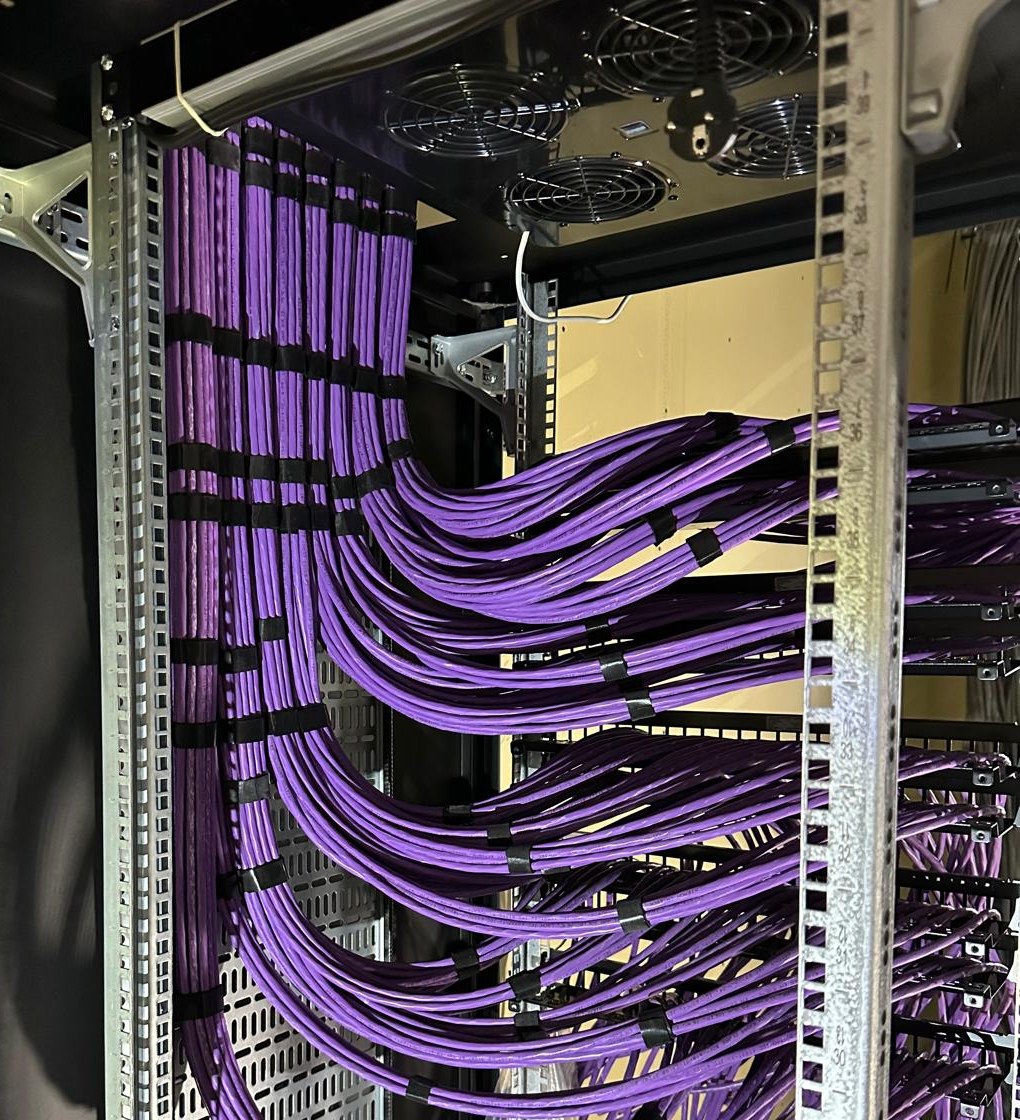 Paarse Cat6a-bundels in bogen naar de achterkant van de patchpanelen